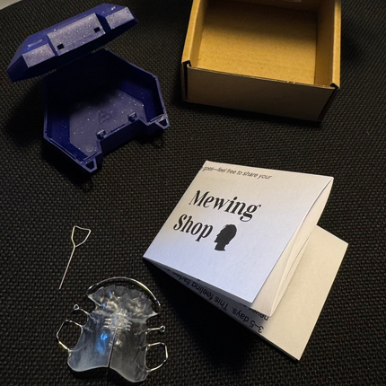 Mewing Shop product packaging with a cardboard box, blue plastic component, and white paper on a textured surface.